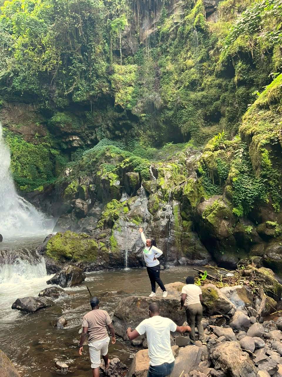 A group exploring the rocks and river below a waterfall