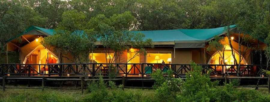Lantern-lit lodge verandah framed by acacia forest