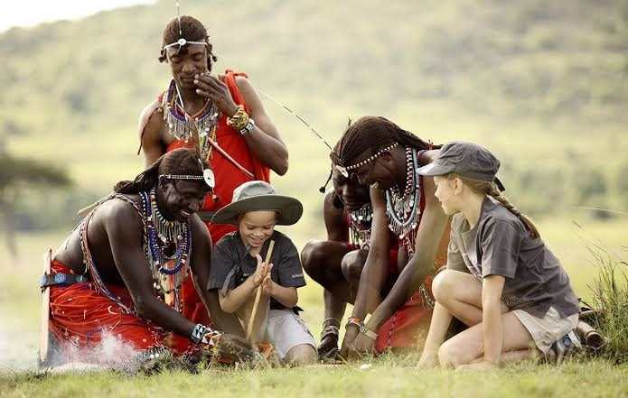 Travellers learning beadwork from Maasai hosts on a cultural visit