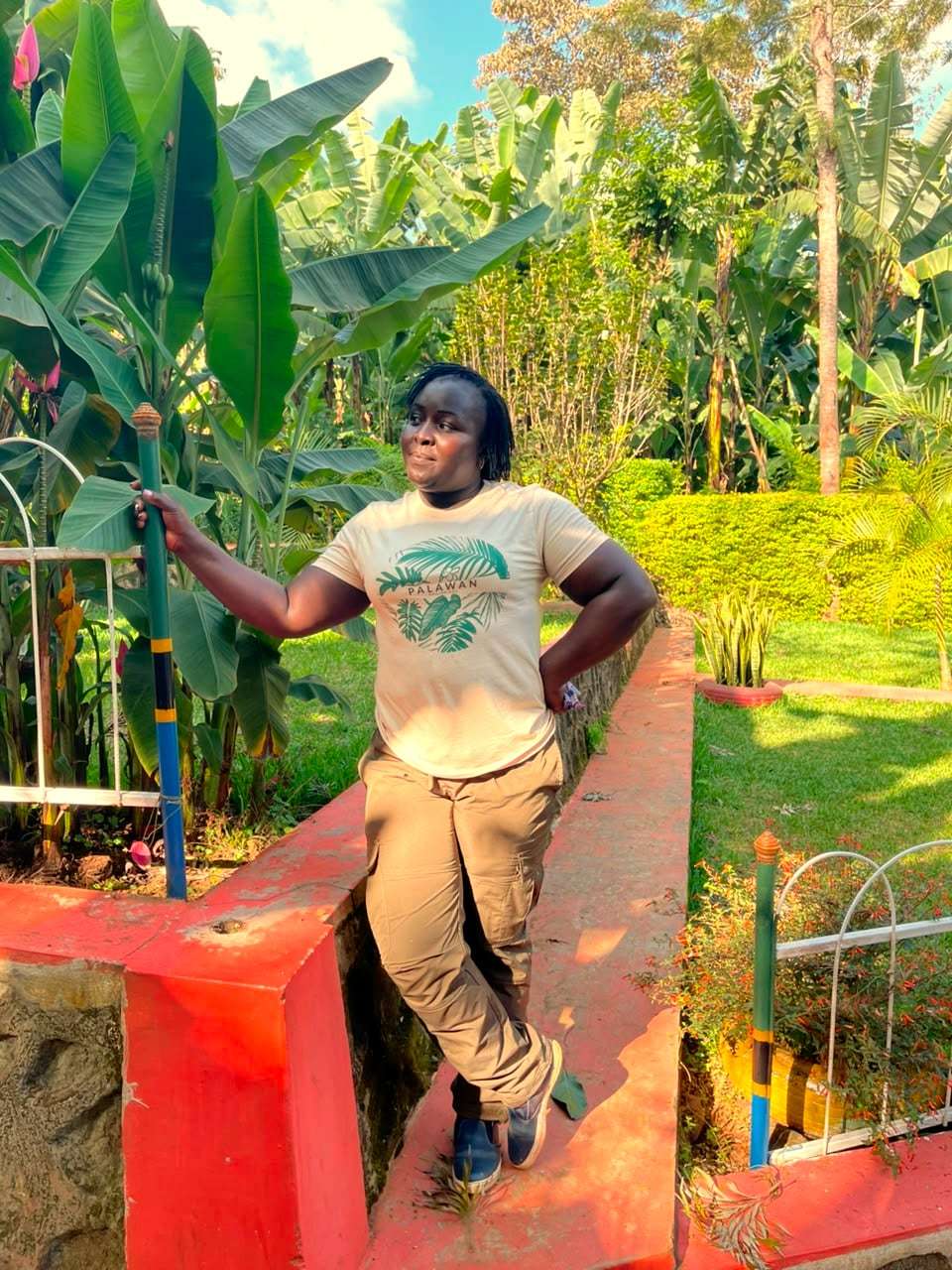 A traveller posing by a garden wall beside a banana plantation
